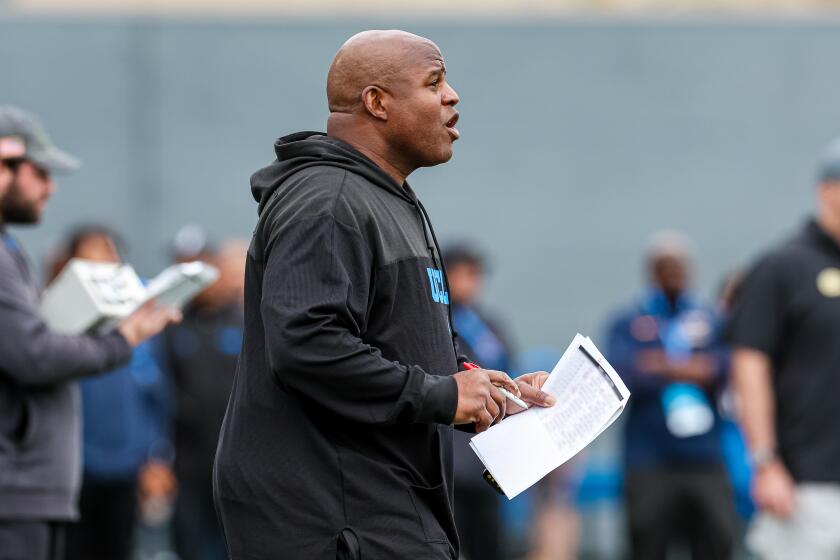 UCLA associate head coach and offensive coordinator Eric Bieniemy walks on the field during spring practice.