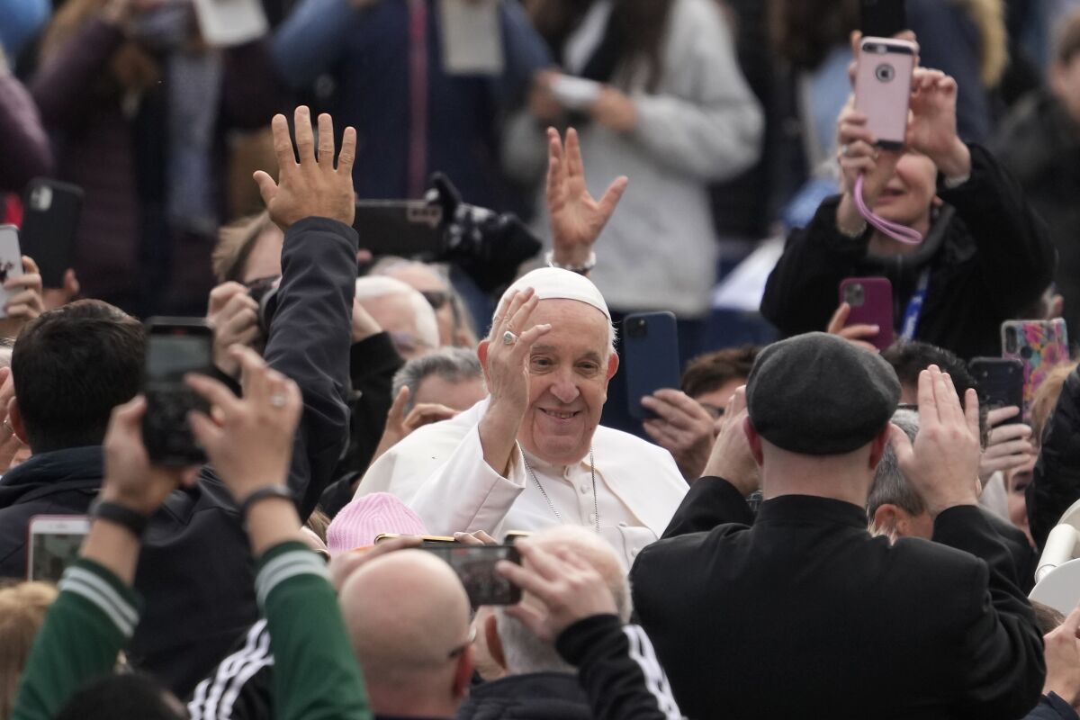 Pope Francis waving as he makes his way through a crowd