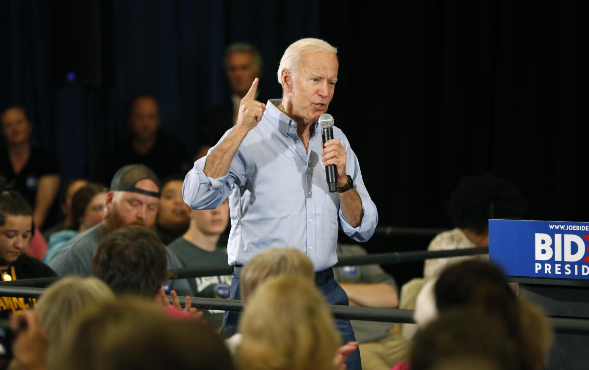 President Biden gestures while holding a microphone.