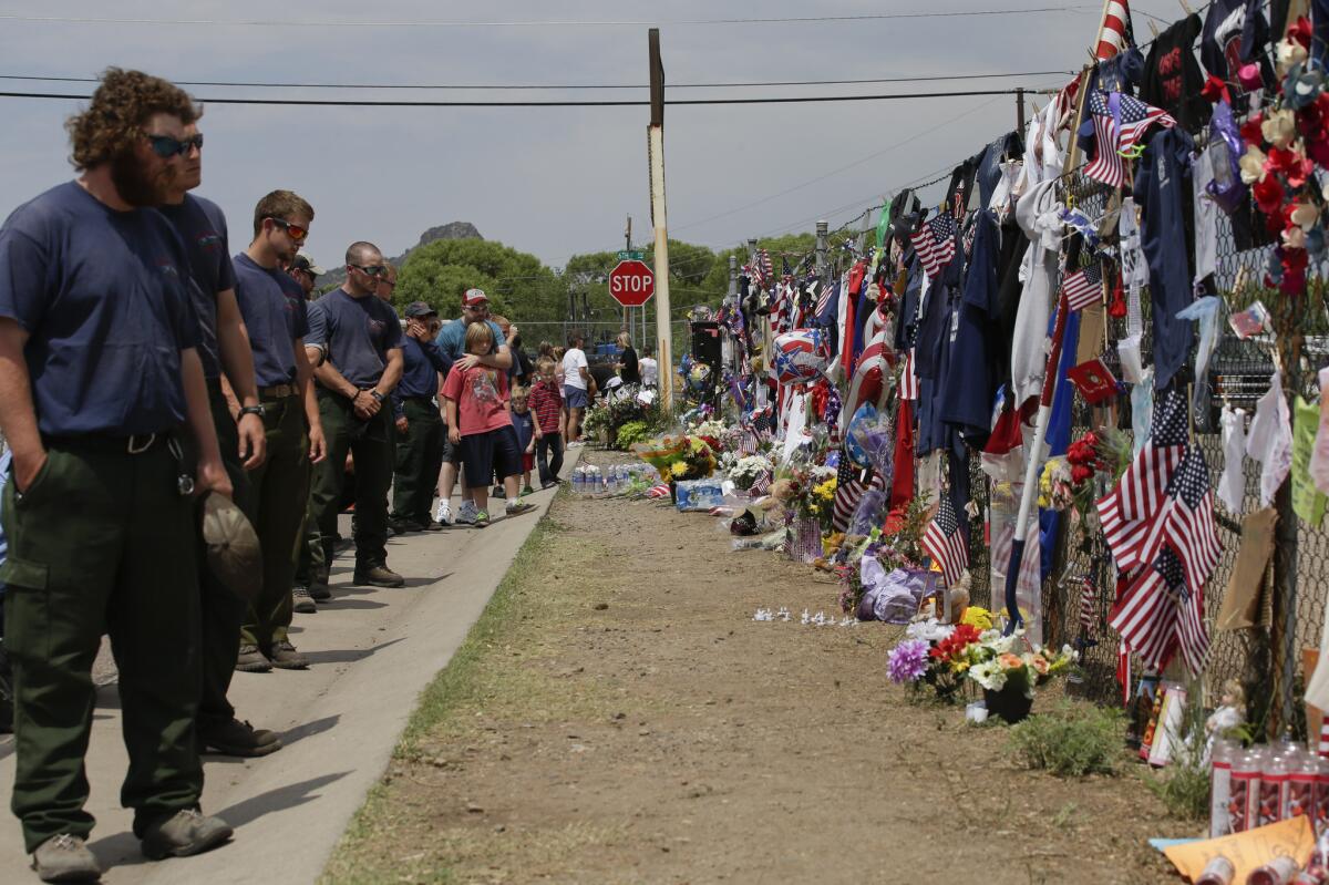 Members of the Centennial Initial Attack Fire Crew from Island Park, Idaho, pay their respects at a memorial outside the Granite Mountain Interagency Hotshot Crew fire station in Prescott, Ariz.