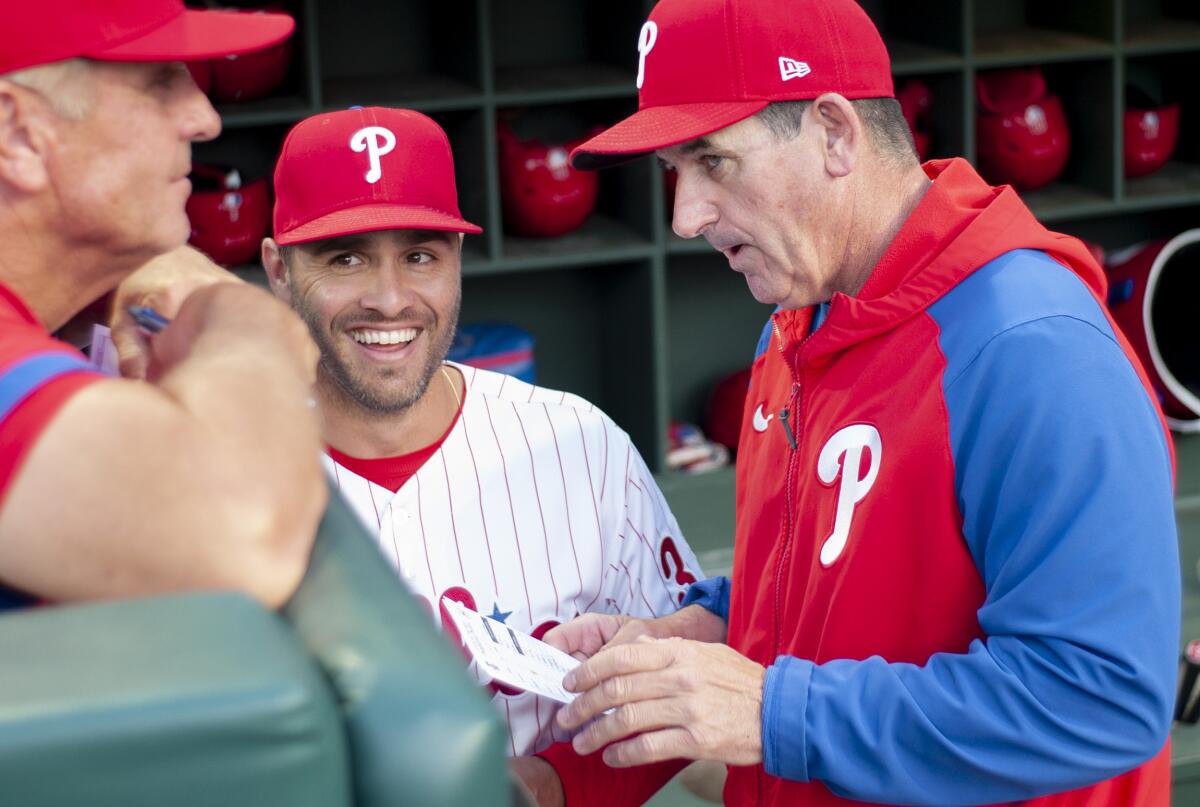 Philadelphia Phillies interim manager Rob Thomson, right, talks with first base coach Paco Figueroa, center, before a baseball game against the Los Angeles Angels, Saturday, June 4, 2022, in Philadelphia. (AP Photo/Laurence Kesterson)