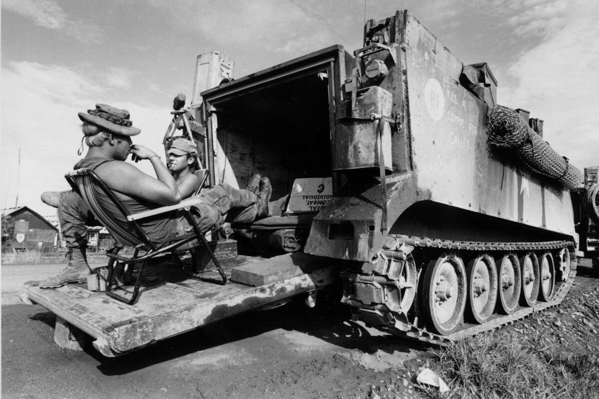 The crew of a U.S. Army armored personnel carrier take time out from the war as they relax in deckchairs on the open rear hatch of their vehicle, at Quang Tri, South Vietnam, May 28, 1971. The inscription on the side of the vehicle reads " Kill a Commie for Calley," in reference to Lt. William Calley. (AP Photo/Nick Ut)