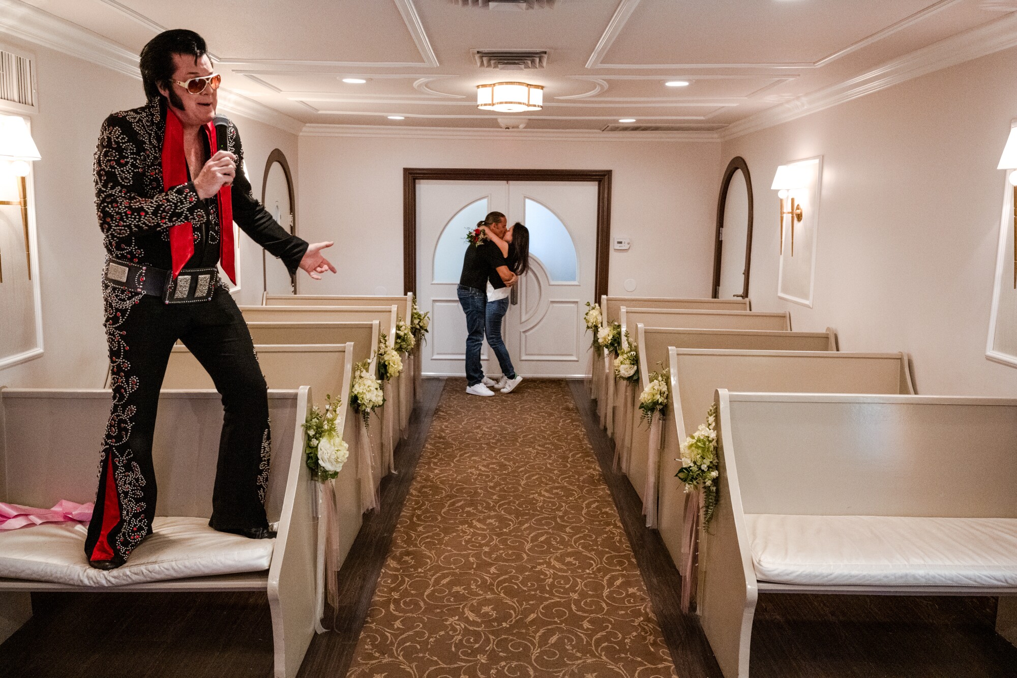 Two people kiss as an Elvis impersonator sings
