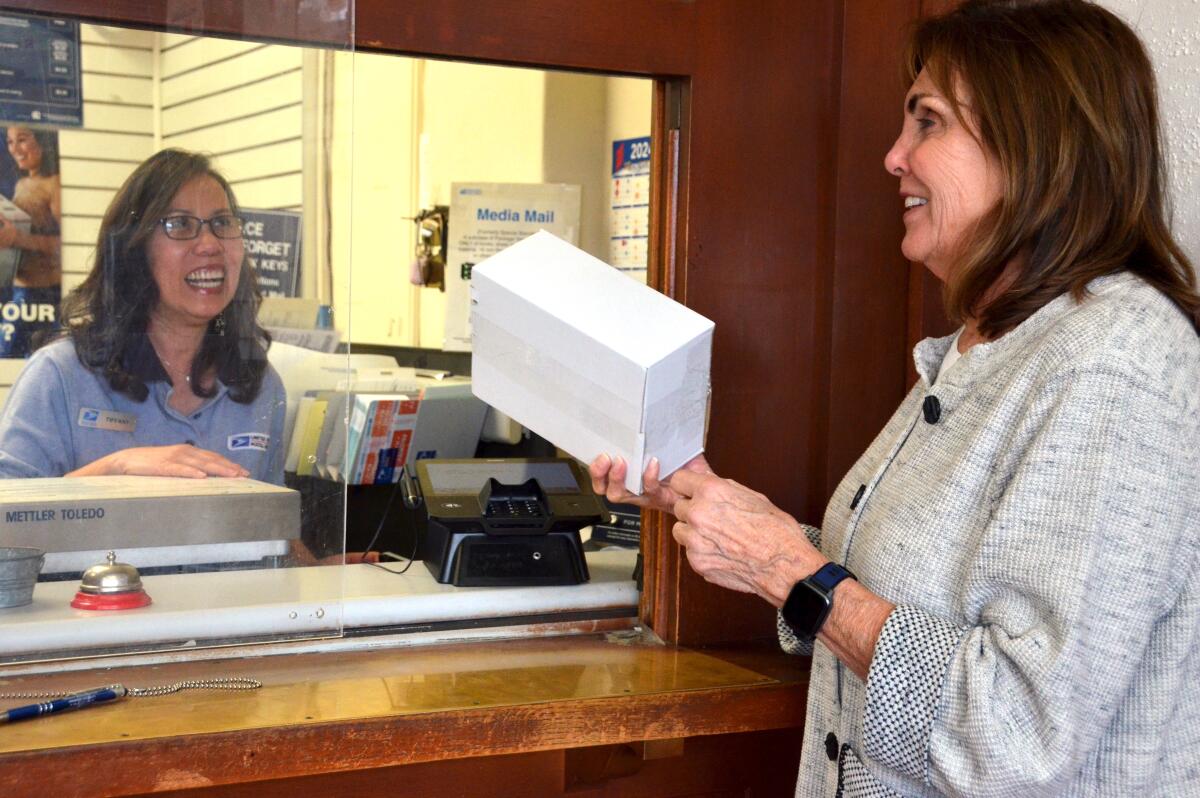 Pat Beek ships a package with the help of postal worker Tiffany Nguyen.