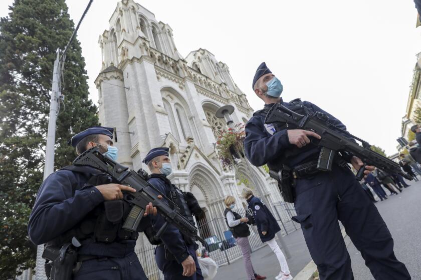 French police officers stand near Notre Dame church in Nice, southern France, Thursday, Oct. 29, 2020. French President Emmanuel Macron has announced that he will more than double number of soldiers deployed to protect against attacks to 7,000 after three people were killed at a church Thursday. (Eric Gaillard/Pool via AP)