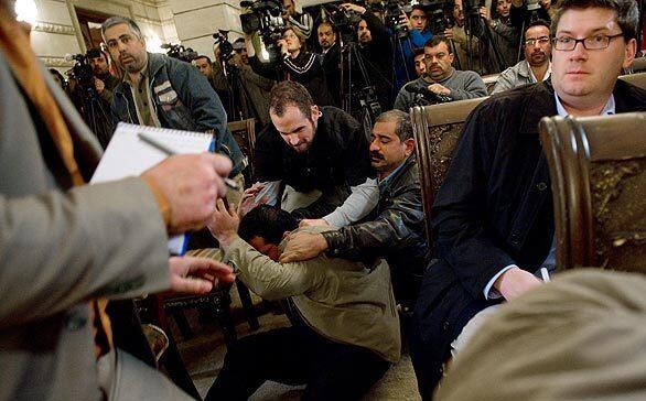 The Iraqi man who threw the shoes is pushed to the ground. President Bush was uninjured in the incident. His unannounced trip to Baghdad marked his fourth visit to the country during his presidency.