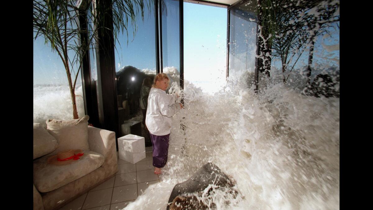 Jan. 30, 1998: Marilyn Lane tries to shut a door as a wave rushes into her Solimar Beach home during a storm.