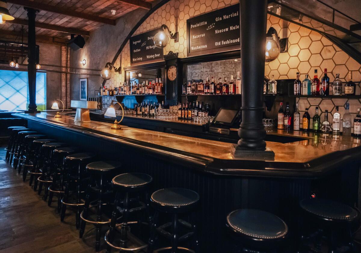 An interior photo taken from the front corner of the bar at Power House Bar. Black stools line the edge of the wooden bar.