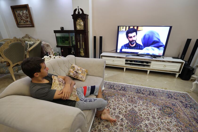 A young man watches an episode of the Iranian television series "Gando" at his home in Iran's capital Tehran on September 6, 2021. - Loathed by Iran's moderates, television spy series "Gando" with its plots mirroring the headlines has gone back on air since ultra-conservative President Ebrahim Raisi's election victory. Named after a local species of crocodile known to ambush its prey, Gando's stars are counter-espionage agents of the Revolutionary Guard, operating from a control room festooned with monitors, much like in the US thriller "24". (Photo by ATTA KENARE / AFP) (Photo by ATTA KENARE/AFP via Getty Images)