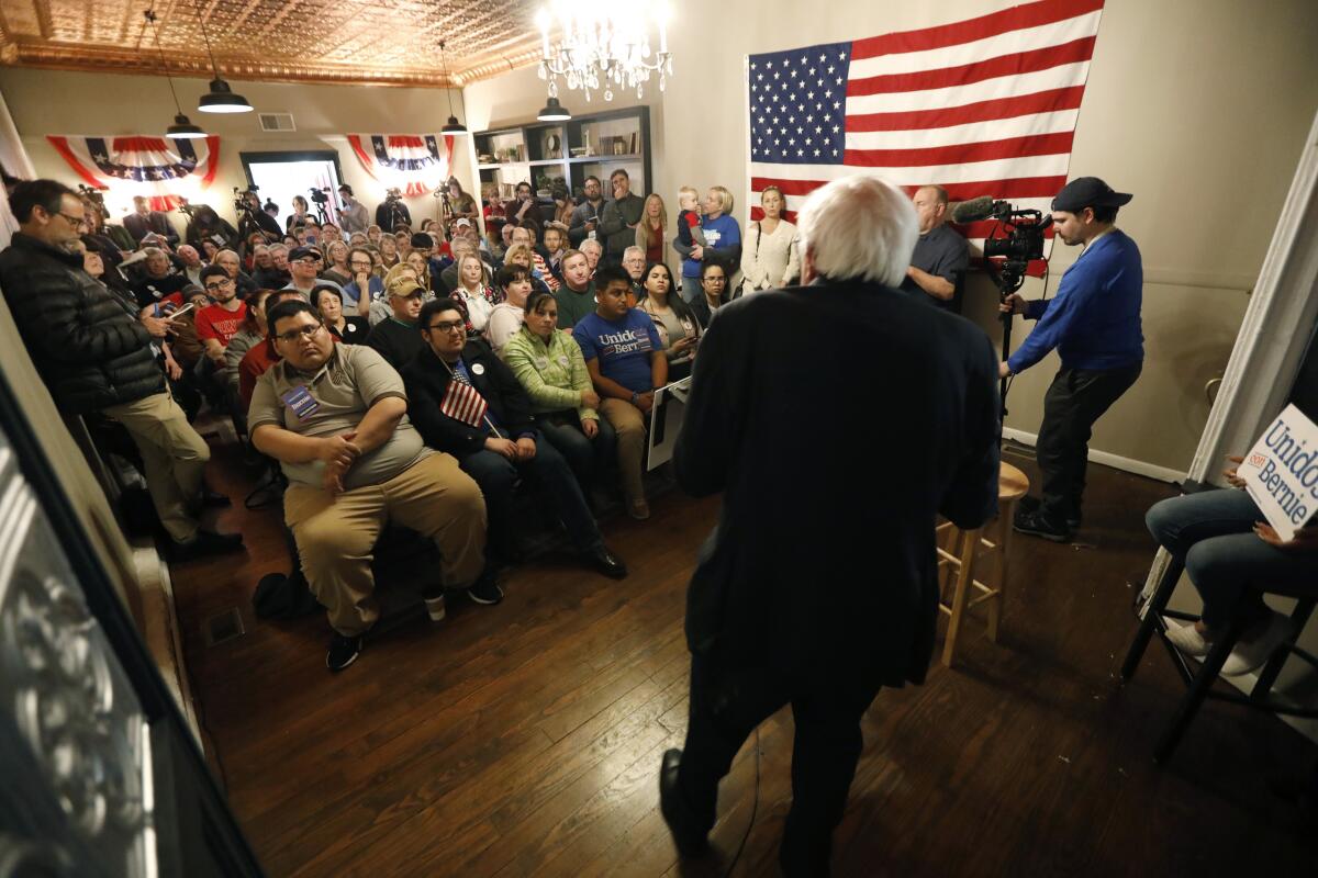 Ángel Ruelas (sentado al frente, a la izquierda) escucha al candidato presidencial demócrata Bernie Sanders durante una parada de campaña en el Black Pearl Cafe, en Muscatine, Iowa, el 2 de enero.