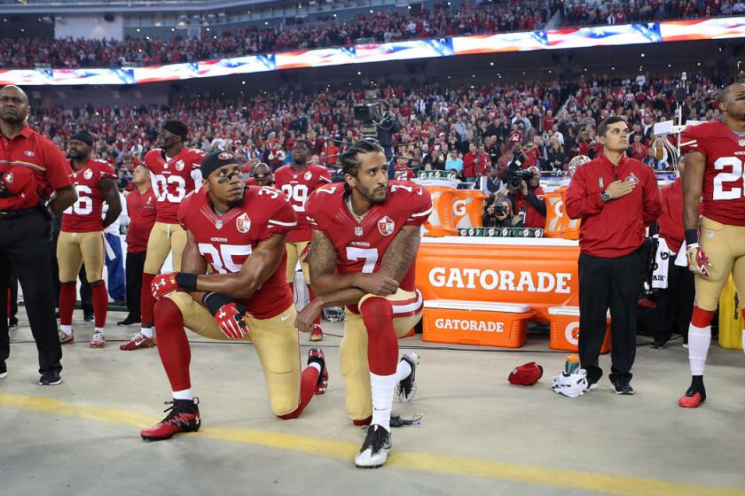 San Francisco 49ers quarterback Colin Kaepernick, center, and Eric Reid take a knee during the national anthem before the team's Sep. 12 game against the Rams.