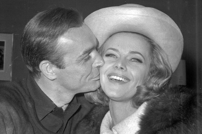 FILE - In this B/W file photo dated March 25, 1964, British actor Sean Connery kisses actress Honor Blackman during a party at Pinewood Film Studios, in Iver Heath, England. Blackman, the actor best-known for playing Bond girl Pussy Galore, hasdied of natural causes unrelated to coronavirus, aged 94, according to an announcement Monday April 6, 2020. (AP Photo, FILE)