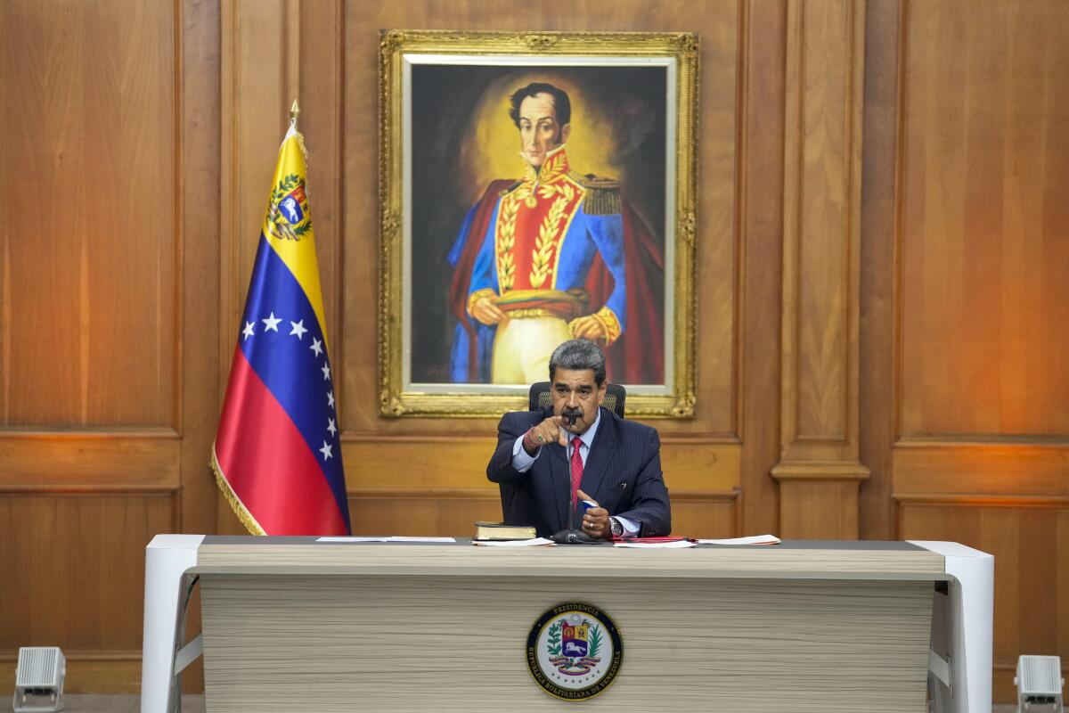 El presidente de Venezuela Nicolás Maduro se sienta frente a una imagen del héroe de la independencia 