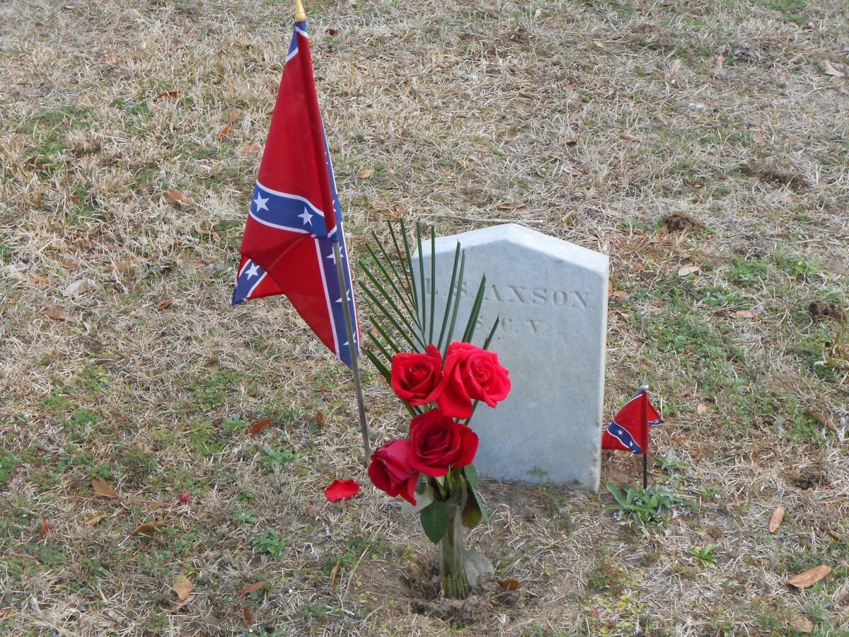 Flowers and miniature confederate flags are seen alongside a gravestone in Charleston's Magnolia Cemetery.