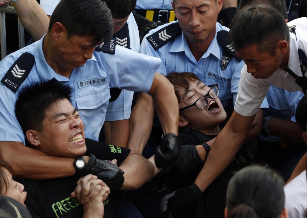 Protesters are taken away by Hong Kong police officers after hundreds of demonstrators staged peaceful sit-ins on a street in the financial district on Wednesday.