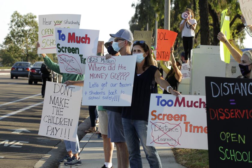 Demonstrators display signs urging officials to open schools during a protest Wednesday, 09/23/2020, in front of the Carlsbad School district headquarters calling for schools in Carslbad to open. photo by Bill Wechter