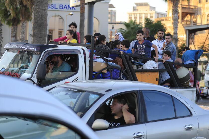 Lebanese citizens who fled the southern villages amid ongoing Israeli airstrikes Monday, sit on their cars at a highway that links to Beirut city, in the southern port city of Sidon, Lebanon, Tuesday, Sept. 24, 2024. (AP Photo/Mohammed Zaatari)