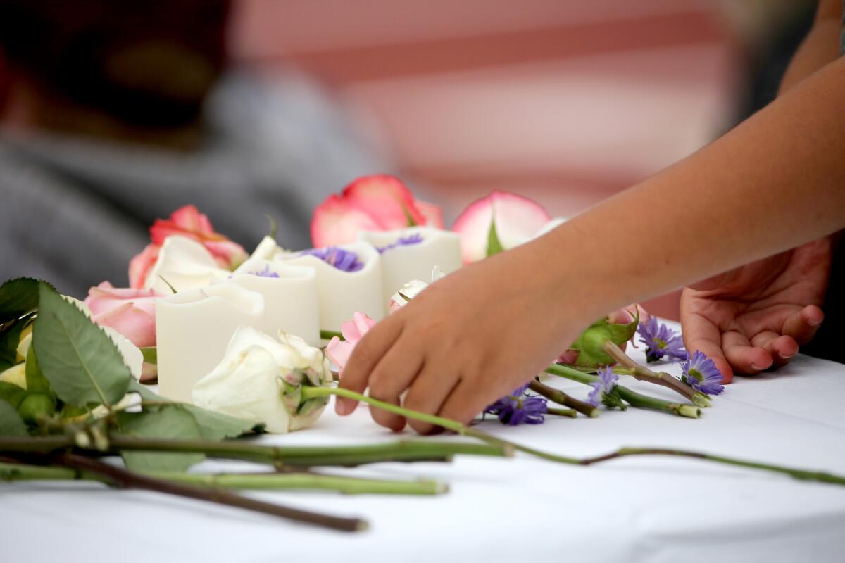A student places a flower on a table during a vigil for El Morro Elementary principal Chris Duddy on Wednesday.
