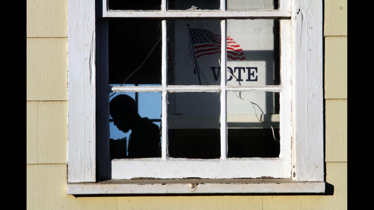 An election worker prepares to greet voters before 7 a.m. at the Angels Gate Cultural Center polling place in San Pedro.