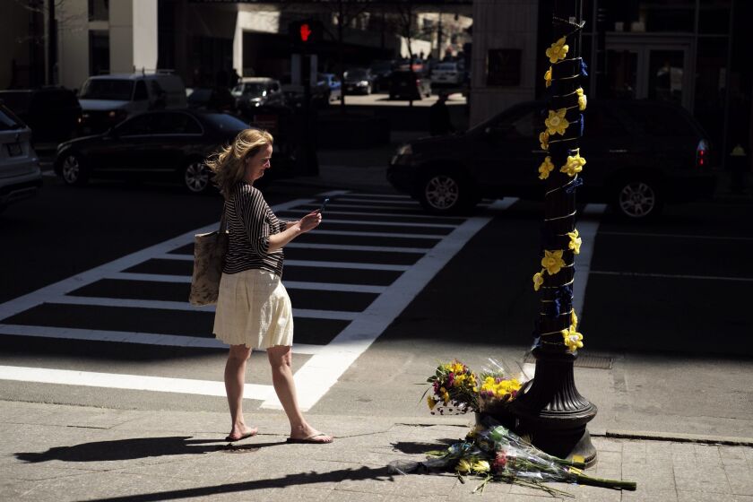 A woman takes a photograph near one of the two sites where bombs exploded near the Boston Marathon finish line two years ago.