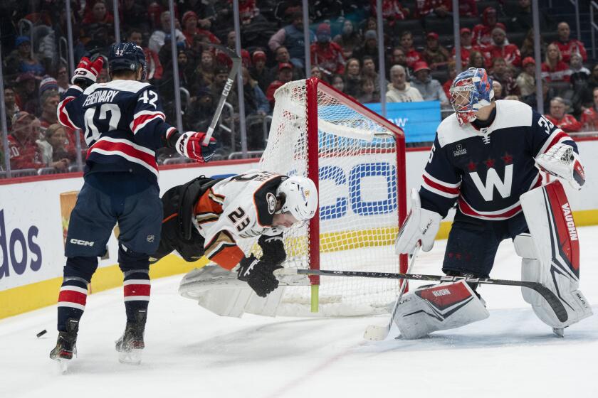 Anaheim Ducks center Mason McTavish (23) is airborne and hits the post as he is checked going around the net by Washington Capitals defenseman Martin Fehervary (42) during the second period of an NHL hockey game Tuesday, Jan. 16, 2024, in Washington. (AP Photo/Manuel Balce Ceneta)