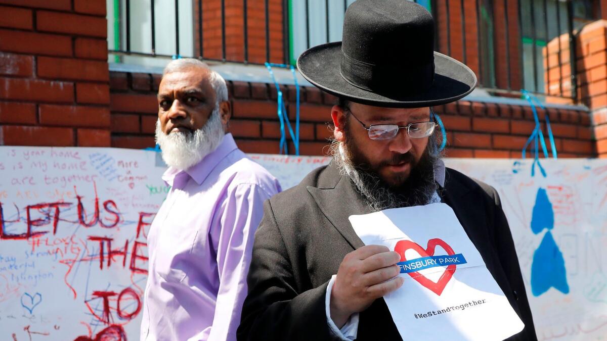 A man holds a sign with a message of solidarity outside Finsbury Park mosque in North London on June 20, 2017.