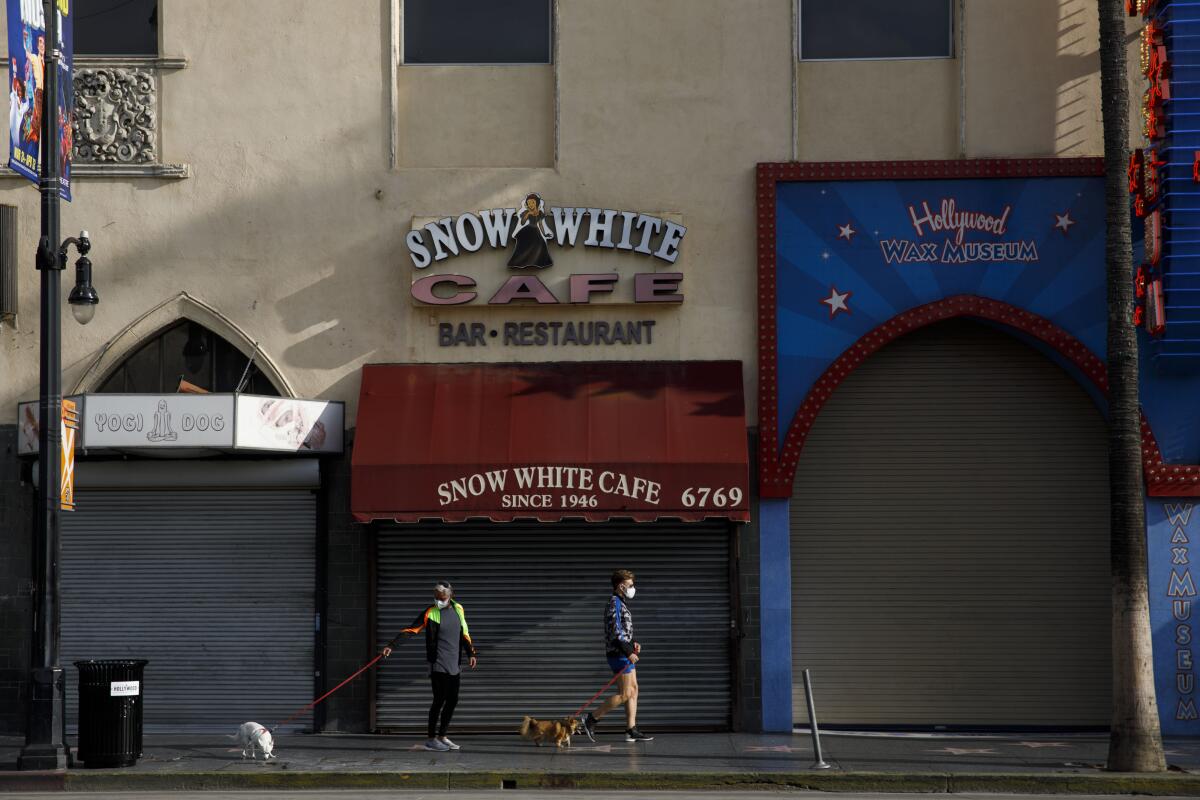 Pedestrians walk dogs past the Snow White Cafe on the Hollywood Walk of Fame in Los Angeles.