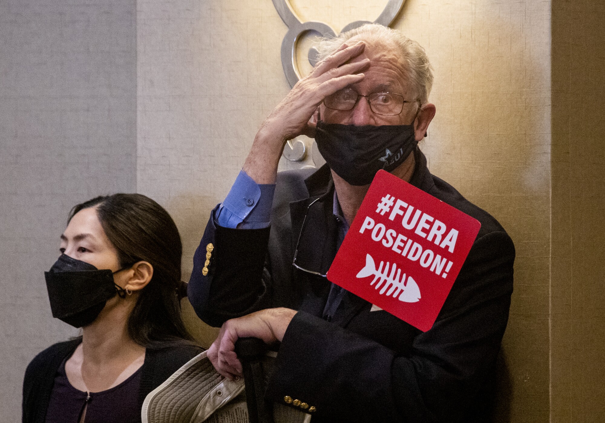 A man holds a sign against the proposed Poseidon desalination project in Huntington Beach 