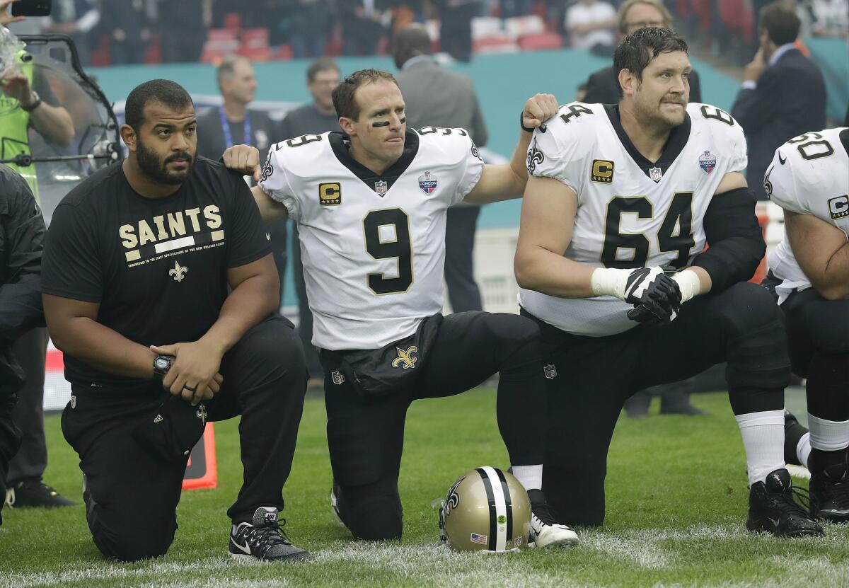 New Orleans Saints' Drew Brees, center, kneels with teammates before the U.S. national anthem at Wembley Stadium in London on Sunday. Saints players stood when the anthem was played.