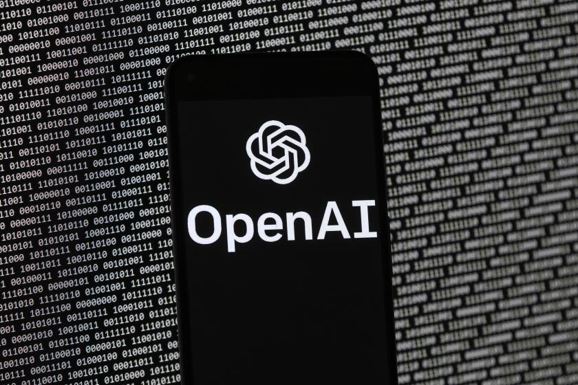 The OpenAI logo appears on a mobile phone in front of a computer screen with random binary data, Thursday, March 9, 2023, in Boston. (AP Photo/Michael Dwyer)