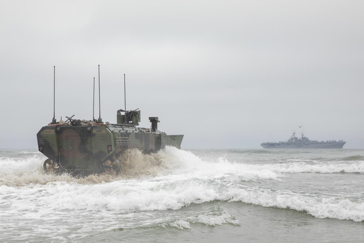 A large, armored vehicle drives into waves.