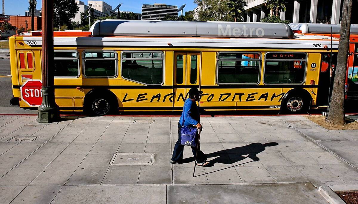 A pedestrian passes a Metro bus that has been painted to look like a school bus as part of the "Arts Matter" campaign.