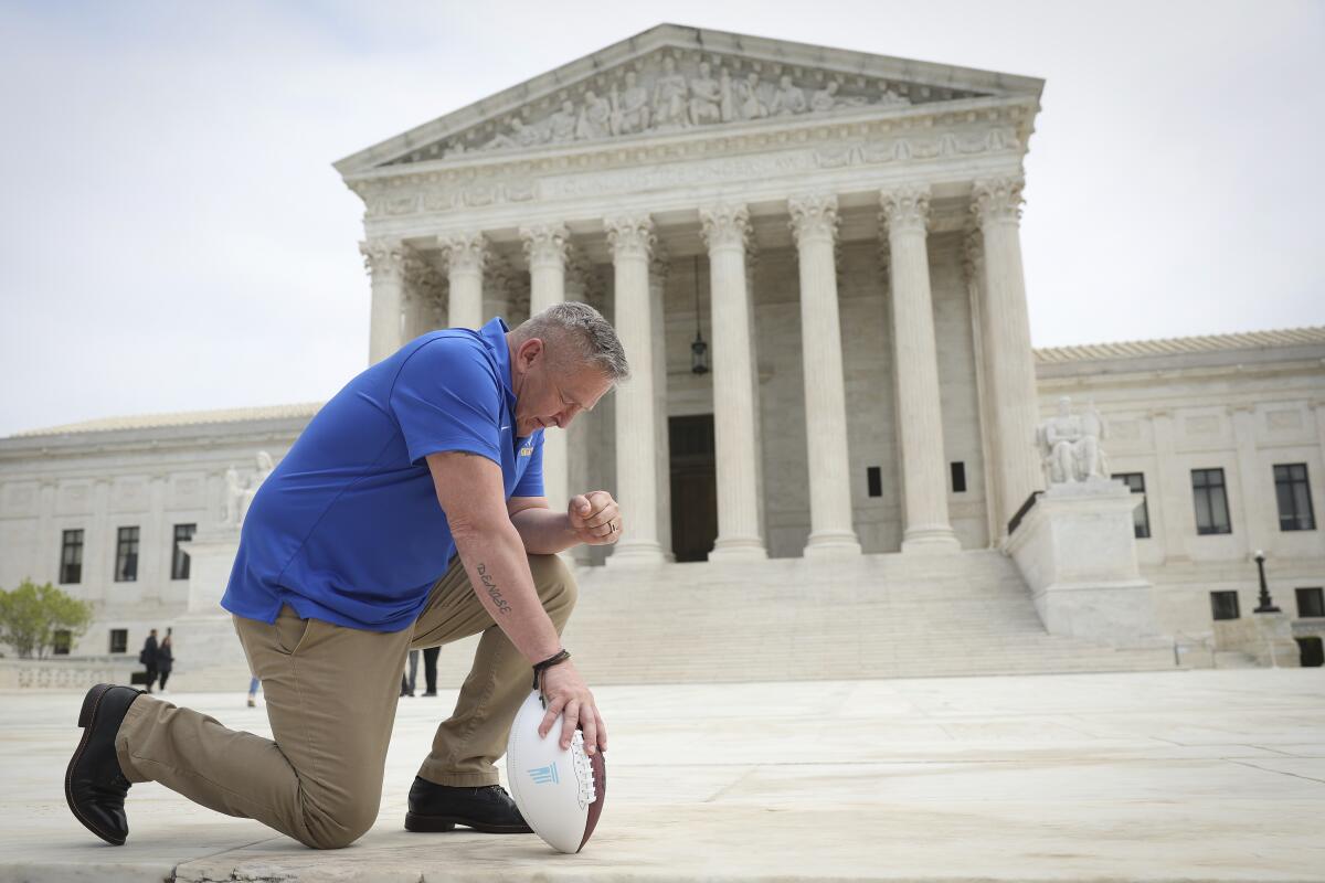 Football coach Joe Kennedy takes a knee in front of the U.S. Supreme Court buiding