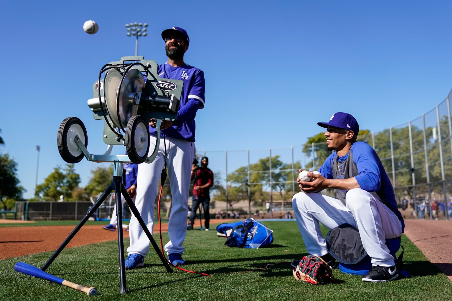 Dodgers right fielder Mookie Betts helps Rancho Cucamonga manager Mark Kertenian feed the machine during a fly ball drill at spring training.