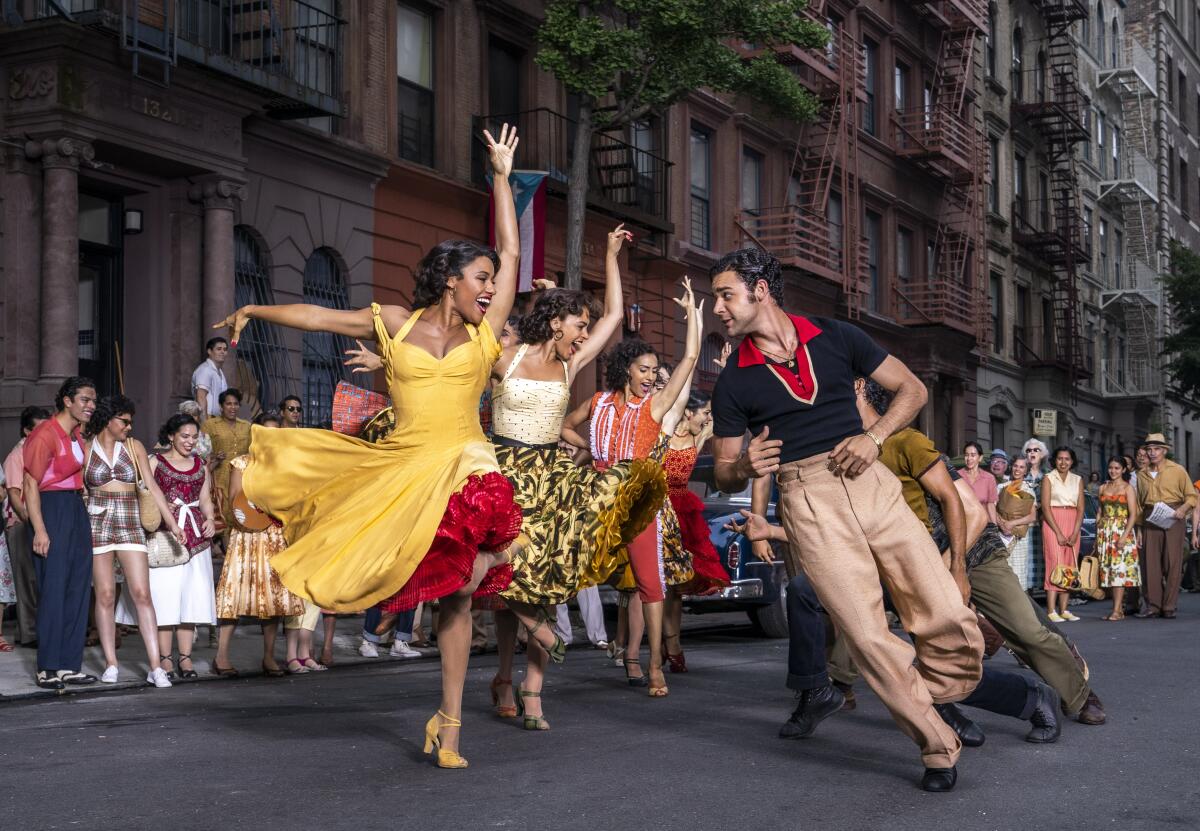 A group of people dance on a city street in colorful outfits.