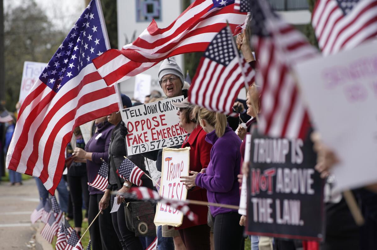 Varias personas se manifiestan afuera de la oficina del senador John Cornyn, en Houston, como parte de una jornada nacional de protestas contra la declaración de emergencia nacional emitida por el presidente Donald Trump.