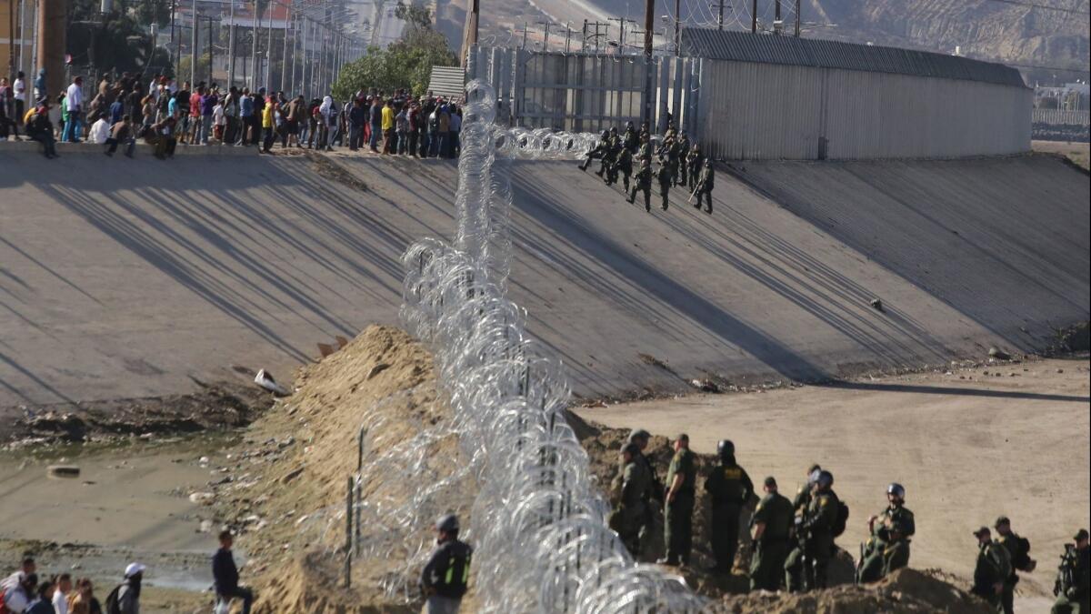 Border police try to prevent groups of people from crossing the border from Tijuana, Mexico, on Nov. 25.