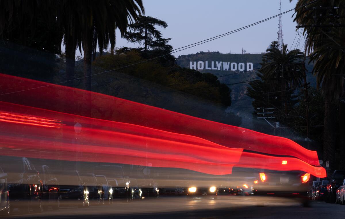 A blur of auto tail lights on a street below the Hollywood sign