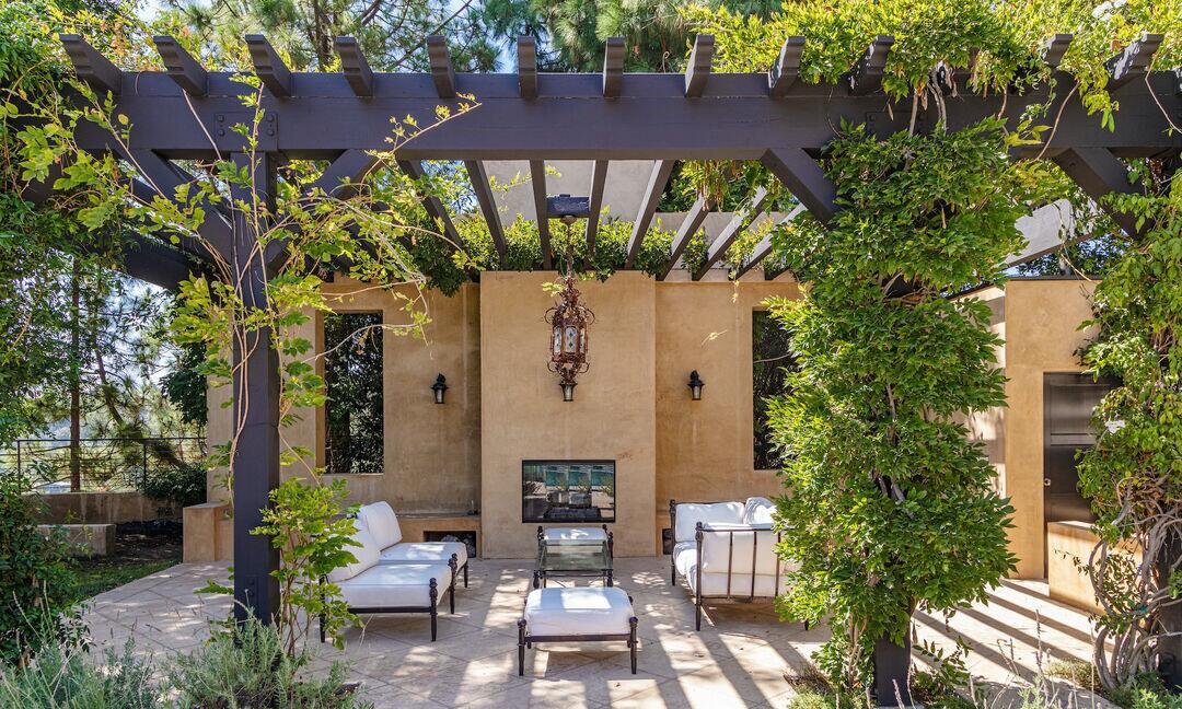 The pergola has chairs and couches in it.