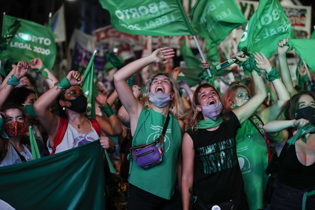 A cheering crowd of protesters wearing green and waving green flags
