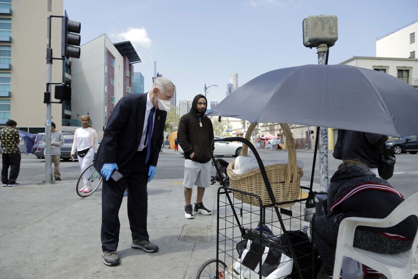 LOS ANGELES, CA - APRIL 03: U.S. District Court judge David O. Carter asks a skid row resident how long the water dispensers have been out of water while touring the area on Friday, April 3, 2020 in Los Angeles, CA. LAPD officer Deon Joseph, who was escorting the judge, said he noticed the water dispenser empty about 1 1/2 weeks ago. Carter is the judge at the center of the Orange County riverbed homeless case. (Myung J. Chun / Los Angeles Times)