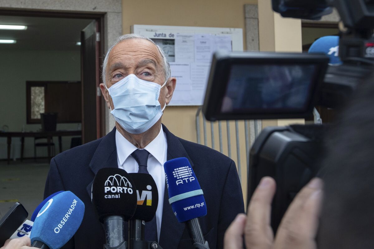 A man in a face mask speaks to reporters