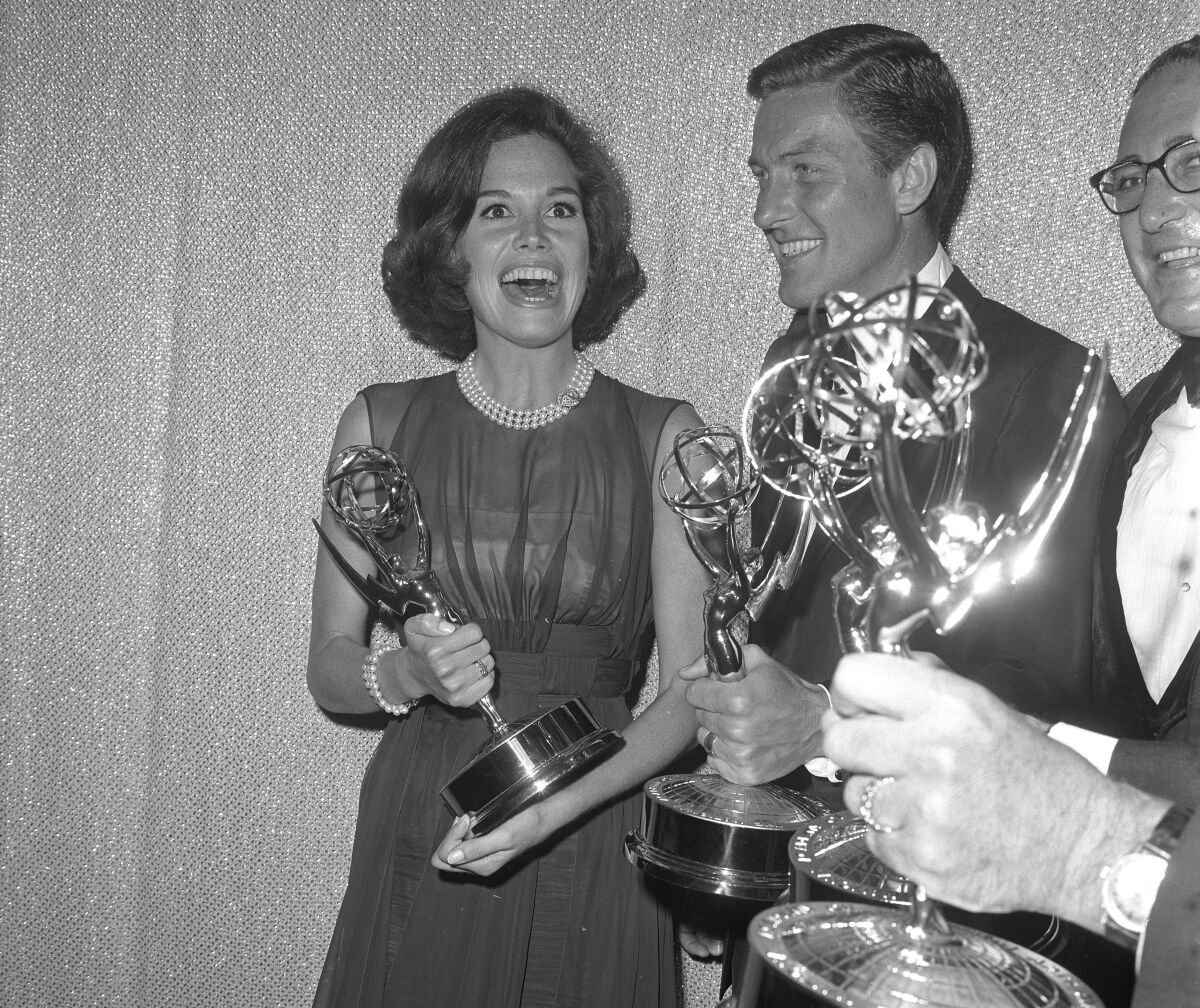 Mary Tyler Moore, Dick Van Dyke, and Sheldon Leonard hold their awards backstage at Emmy Awards in 1964.