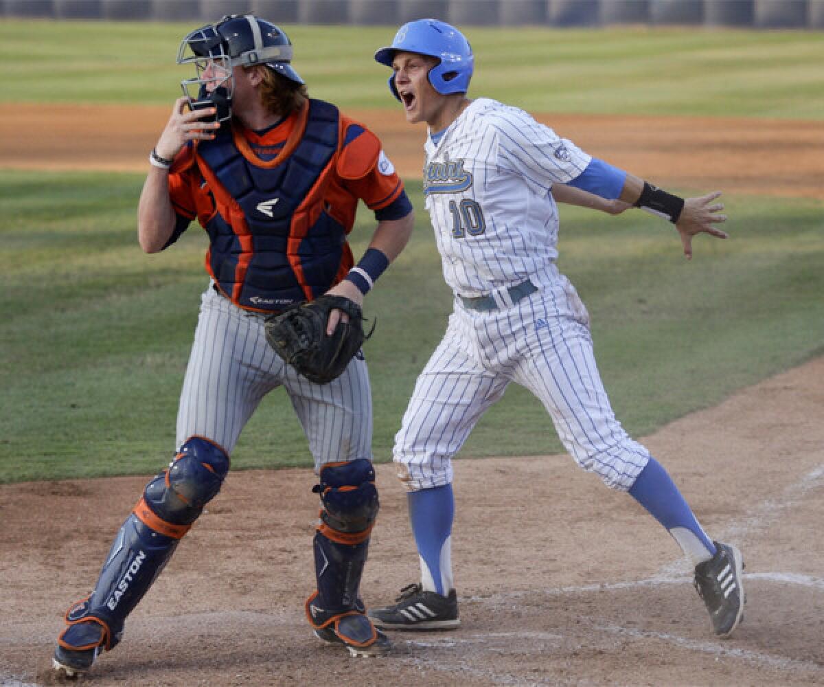 UCLA's Pat Valaika scores behind Cal State Fullerton catcher Chad Wallach during the first inning of the Bruins' 3-0 victory Saturday to earn a spot in the College World Series.