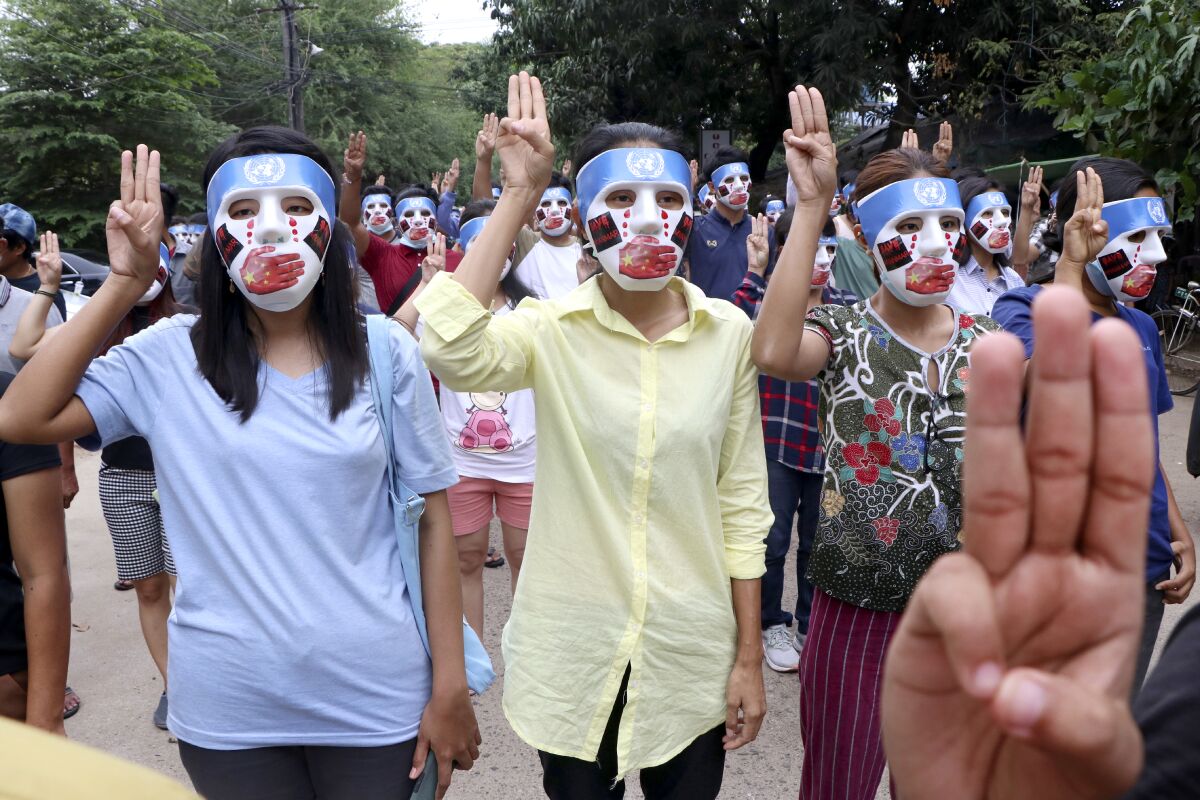 Demonstrators wearing masks flash a three-fingered symbol of resistance.