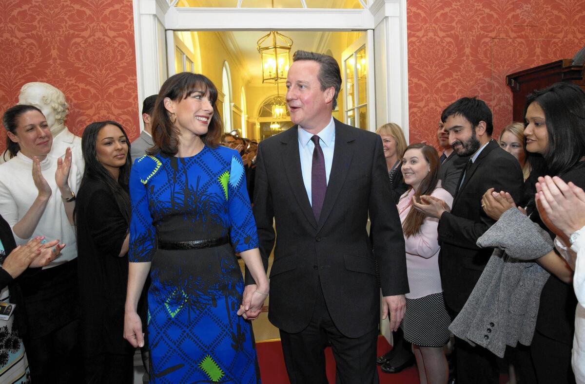 British Prime Minister David Cameron and his wife, Samantha, are applauded by staff members at 10 Downing Street after visiting Queen Elizabeth II a day after elections.