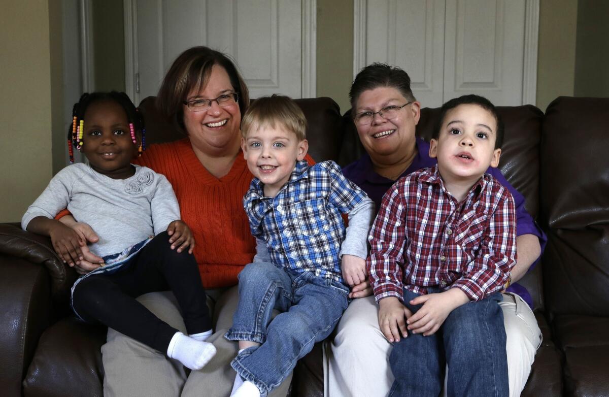April DeBoer, left, and Jayne Rowse pose at their Hazel Park, Mich., home with their adopted children, from left: Ryanne, 3, Jacob, 3, and Nolan, 4.