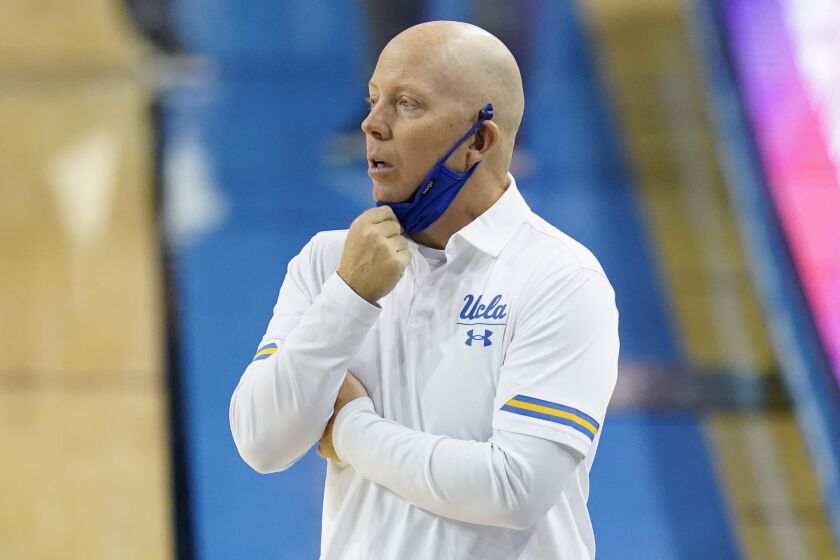 UCLA coach Mick Cronin adjusts his mask on the sideline during the first half of the team's.