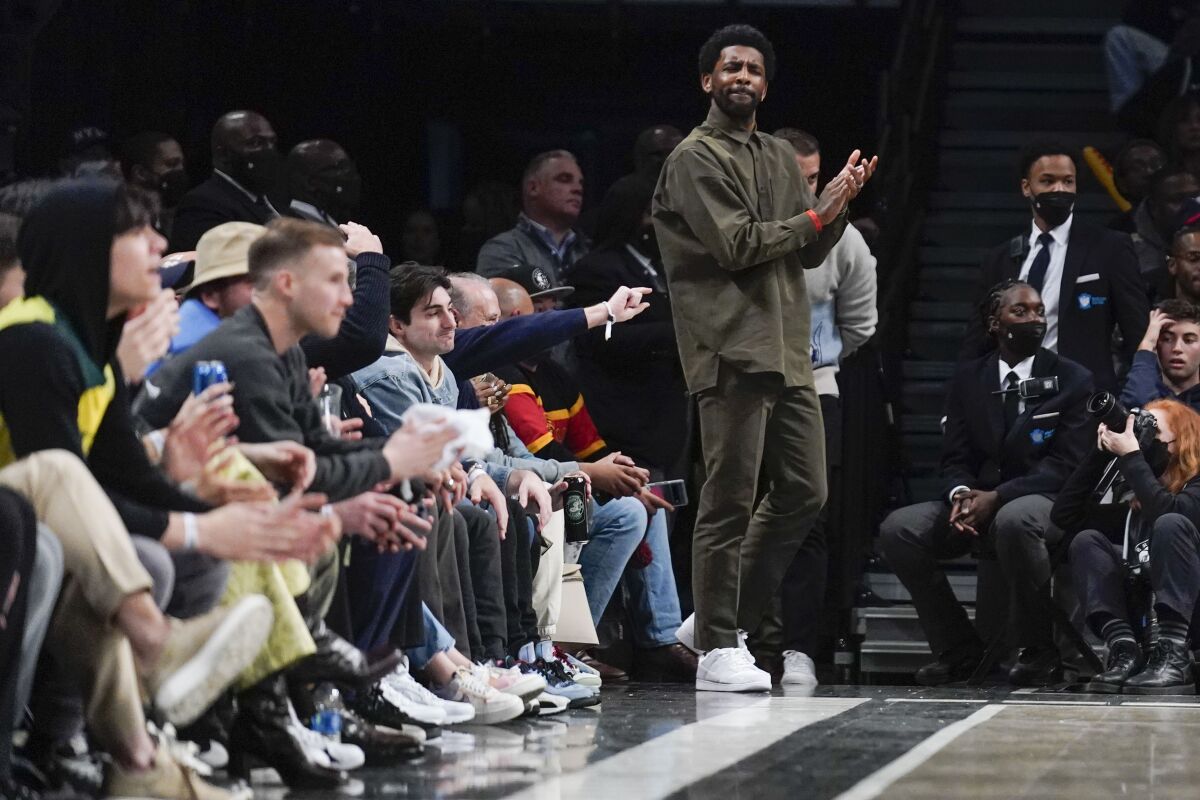 Brooklyn Nets' Kyrie Irving watches the game from his seats during the second half of the NBA basketball game between the Brooklyn Nets and the New York Knicks at the Barclays Center, Sunday, Mar. 13, 2022, in New York. The Nets defeated the Knicks 110-107. (AP Photo/Seth Wenig)