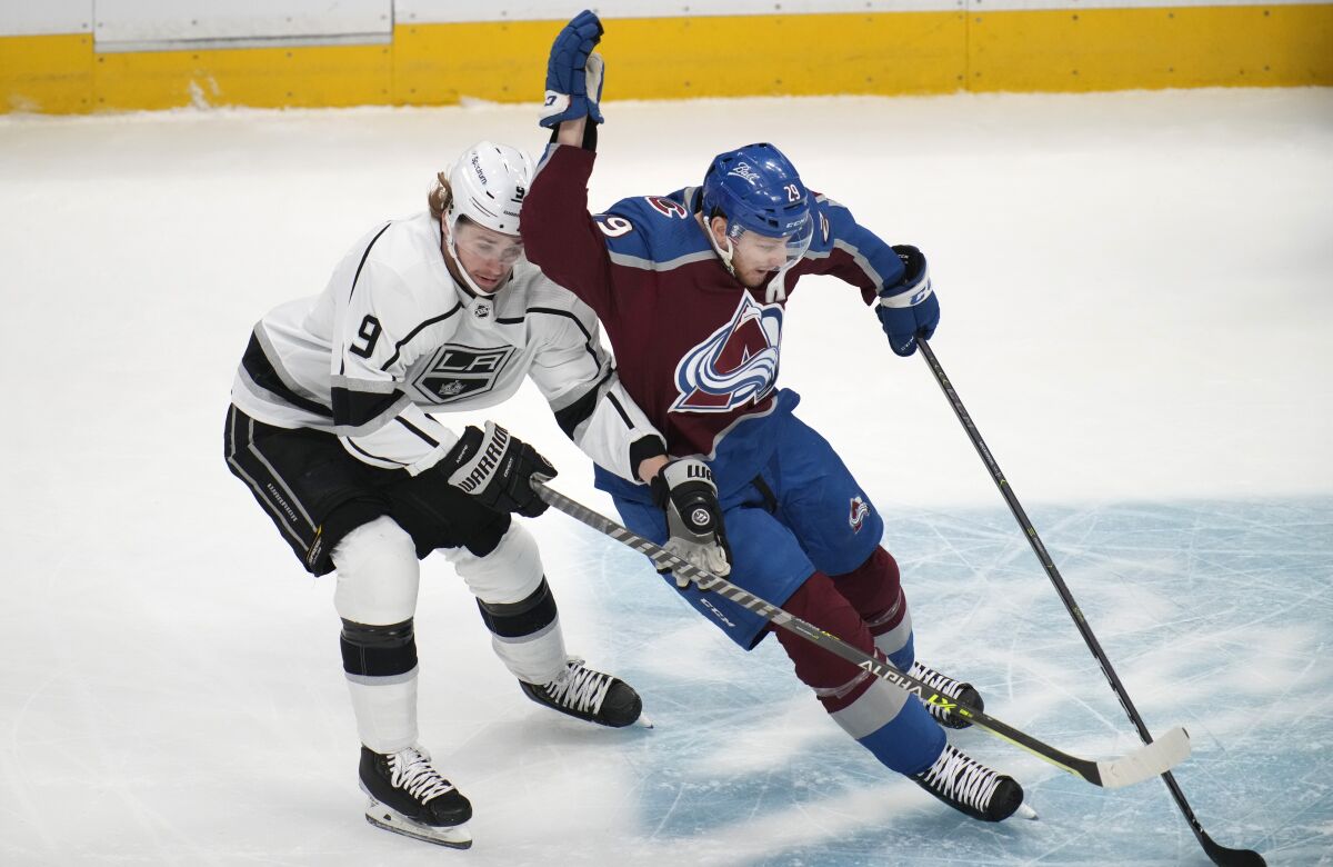 Colorado Avalanche center Nathan MacKinnon, right, fights for control of the puck with Los Angeles Kings center Adrian Kempe in the first period of an NHL hockey game Wednesday, April 13, 2022, in Denver. (AP Photo/David Zalubowski)